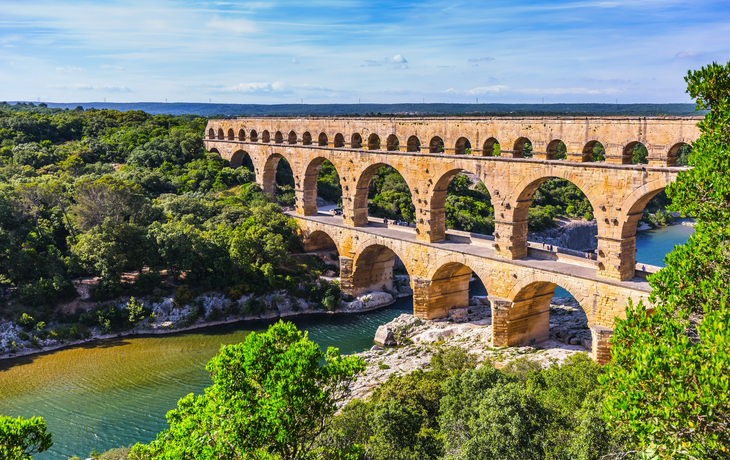 Pont du Gard, römischer Aquädukt über einen Fluss in bewaldeter Landschaft.