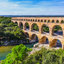 Pont du Gard, römischer Aquädukt über einen Fluss in bewaldeter Landschaft.