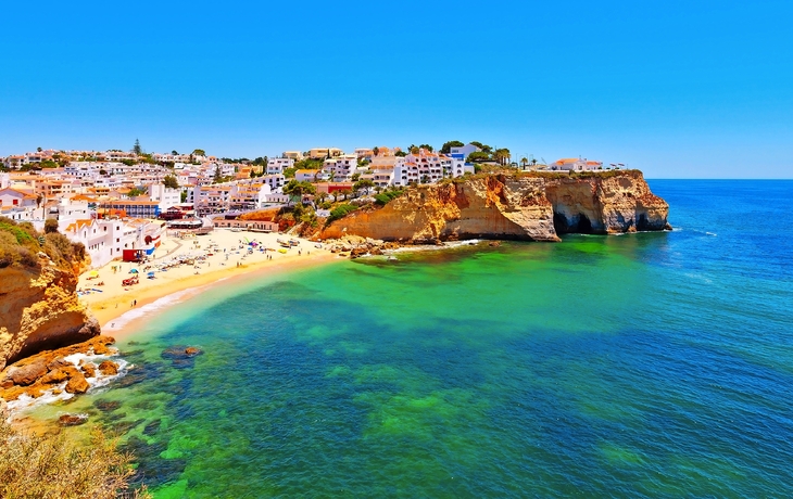 Küstenstadt mit Strand und Steilklippen am klaren, blauen Meer.