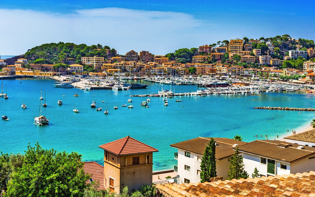 Küstenstadt mit Hafen und Segelbooten an sonnigem Tag.