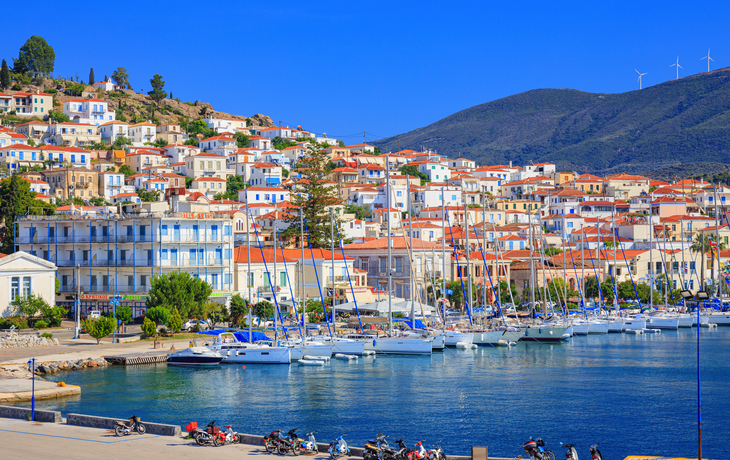 Blick auf einen malerischen Hafen mit Segelbooten und bunten Häusern im Hintergrund.