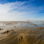 Weite Wattlandschaft auf Föhr mit blauem Himmel.