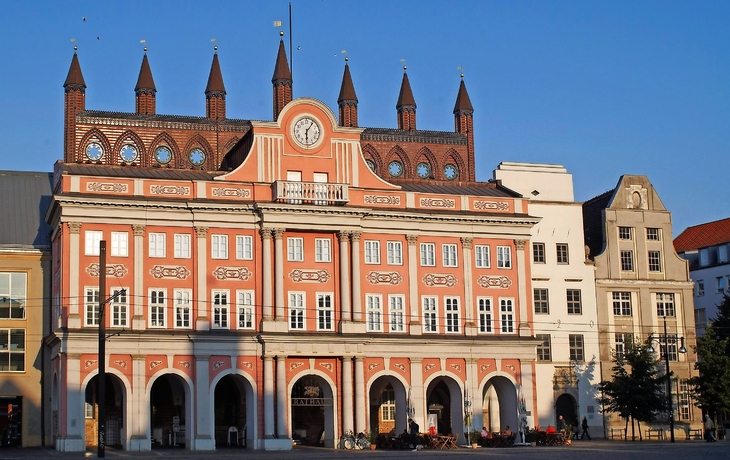 Historisches Gebäude mit Uhr und verziertem Dach im Abendlicht.