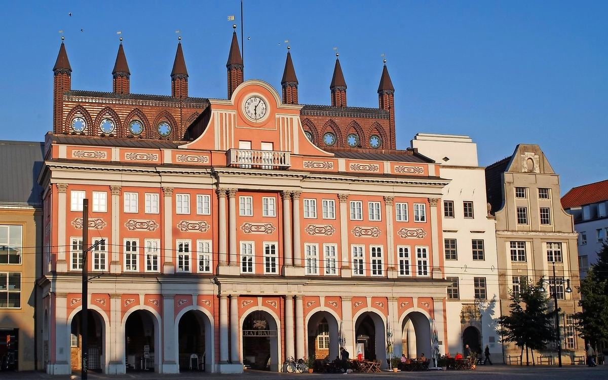 Historisches Gebäude mit Uhr und verziertem Dach im Abendlicht.