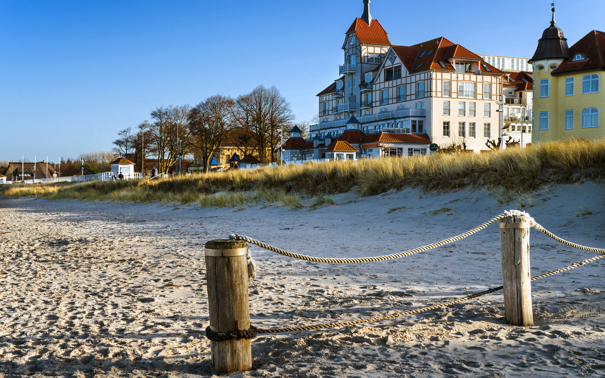 Strand mit Dünen und historischer Gebäudekulisse bei blauem Himmel