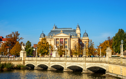 Theatergebäude hinter Fluss mit Brücke an einem sonnigen Herbsttag.