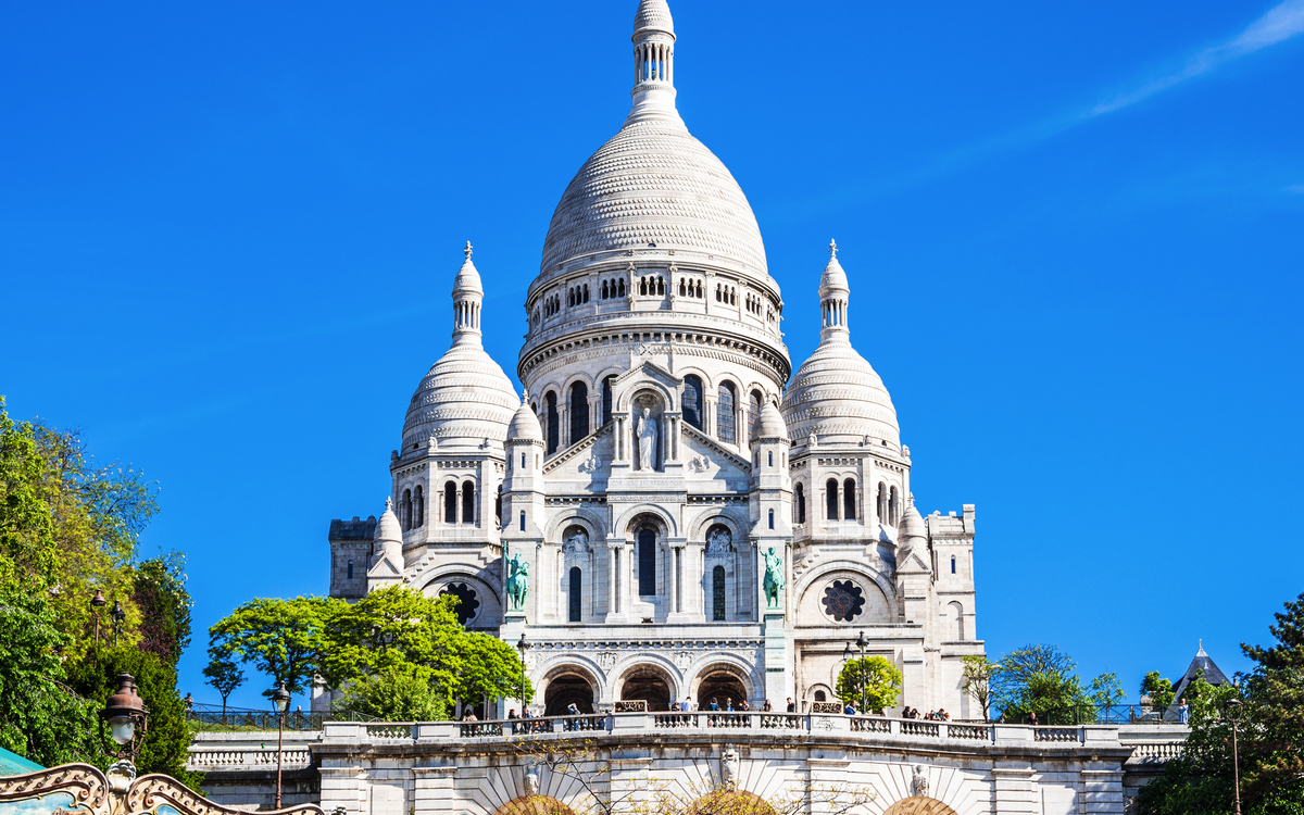 Basilika Sacré-Cœur vor blauem Himmel in Paris.