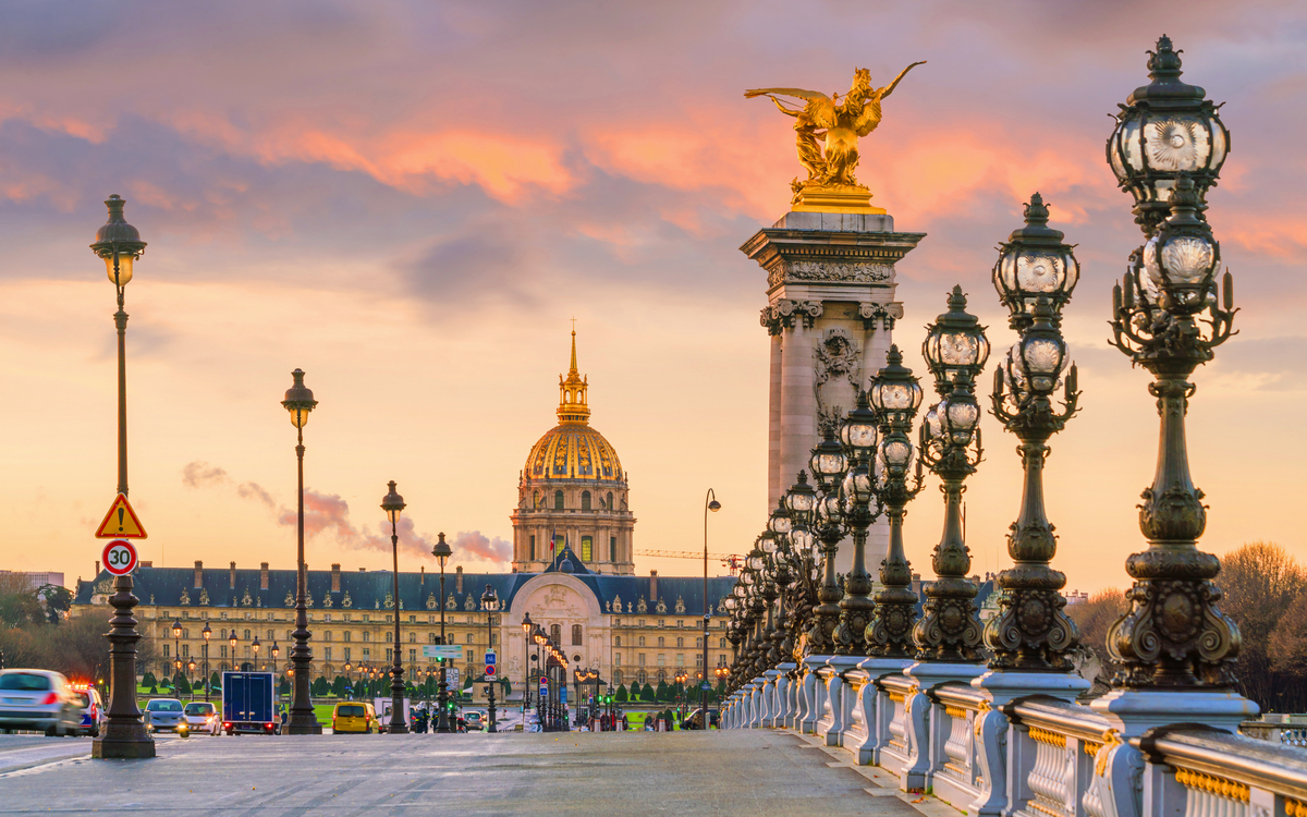 Blick auf die Pont Alexandre III in Paris bei Sonnenuntergang mit Les Invalides im Hintergrund.