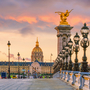 Blick auf die Pont Alexandre III in Paris bei Sonnenuntergang mit Les Invalides im Hintergrund.