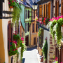 Schmale, malerische Gasse mit Fachwerkhäusern und blühenden Blumen.