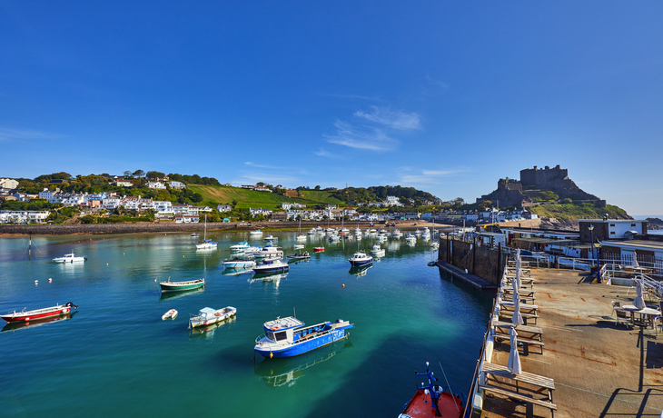 Boote im Hafen mit Burg im Hintergrund bei blauem Himmel