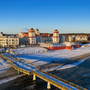 Winterlicher Strand mit Seebrücke und Gebäuden im Hintergrund bei Sonnenuntergang.