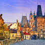 Historische Brücke mit Statuen und alten Gebäuden im Hintergrund. Prag