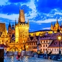 Karlsbrücke in Prag bei Sonnenuntergang mit Menschen und blauem Himmel.
