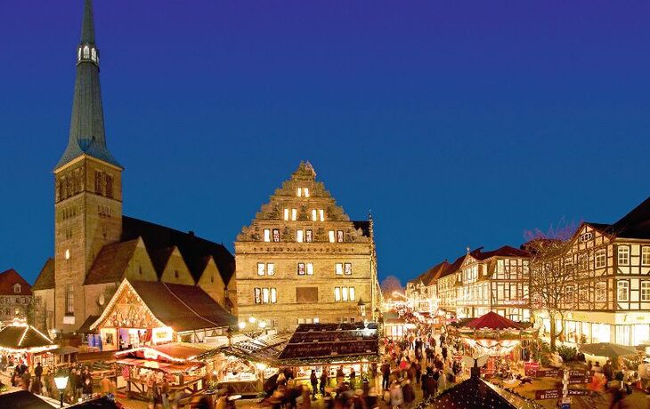 Weihnachtsmarkt an der Marktkirche St. Nicolai mit vielen Ständen und Besuchern bei Nacht.