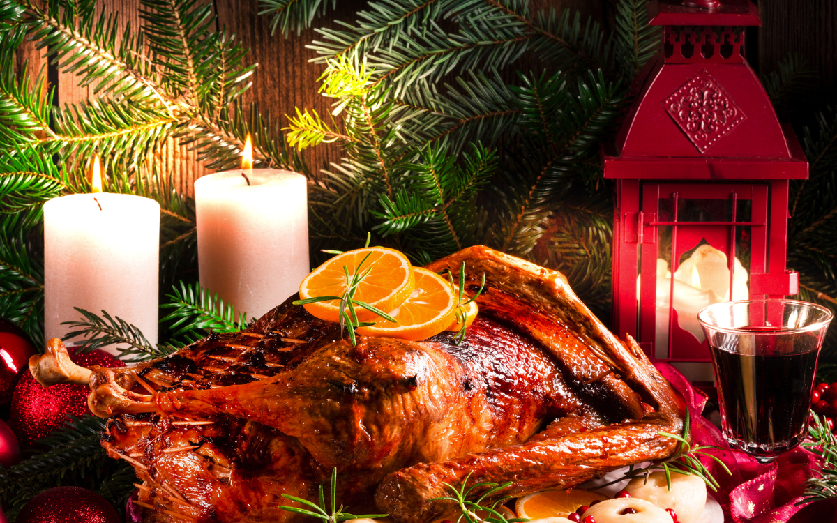 Festlich gedeckter Tisch mit gebratenem Truthahn, Kerzen und Weihnachtsschmuck.