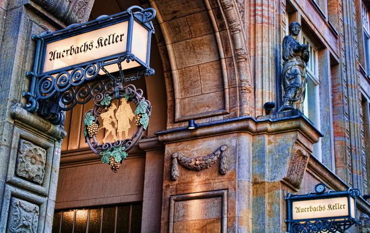 Eingang zu Auerbachs Keller mit dekorativem Schild und Skulptur an der Fassade. Auerbachs Keller in Leipzig