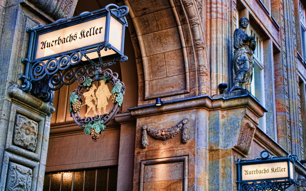 Eingang zu Auerbachs Keller mit dekorativem Schild und Skulptur an der Fassade. Auerbachs Keller in Leipzig