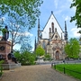 Gotische Kirche mit Park und Statue im Vordergrund. Thomaskirche Leipzig
