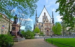 Gotische Kirche mit Park und Statue im Vordergrund. Thomaskirche Leipzig