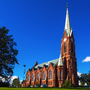 Mikkeli-Kathedrale in Finnland an einem klaren Tag mit blauem Himmel und umliegenden Bäumen.