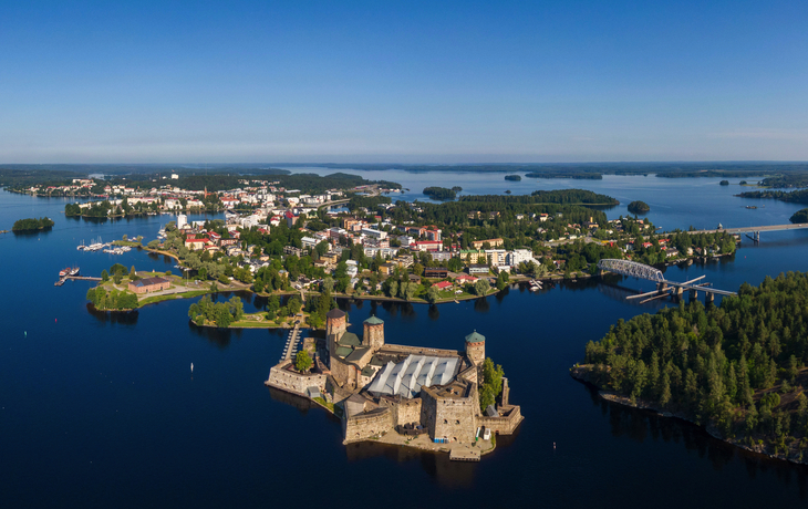 Luftaufnahme einer Festung auf einer Insel im See, umgeben von Stadt und Wald. Savonlinna