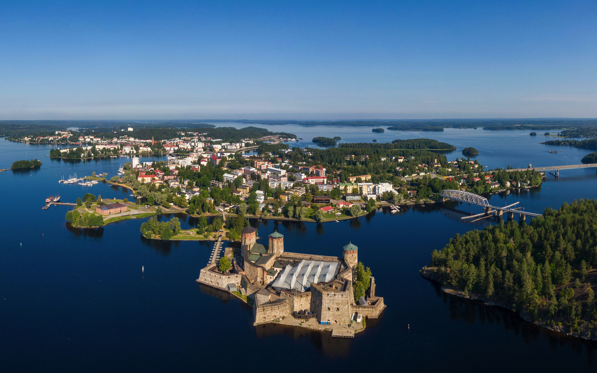 Luftaufnahme einer Festung auf einer Insel im See, umgeben von Stadt und Wald. Savonlinna