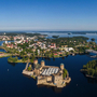 Luftaufnahme einer Festung auf einer Insel im See, umgeben von Stadt und Wald. Savonlinna