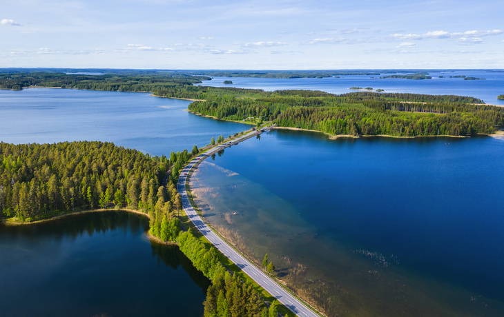 Straße durch eine Seenlandschaft mit bewaldeten Inseln aus der Vogelperspektive. finnische Seenplatte