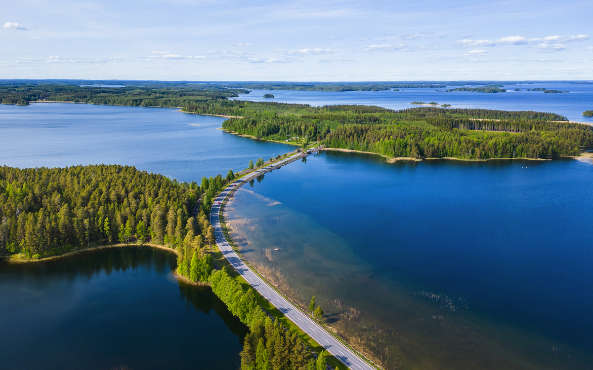 Straße durch eine Seenlandschaft mit bewaldeten Inseln aus der Vogelperspektive. finnische Seenplatte