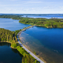 Straße durch eine Seenlandschaft mit bewaldeten Inseln aus der Vogelperspektive. finnische Seenplatte