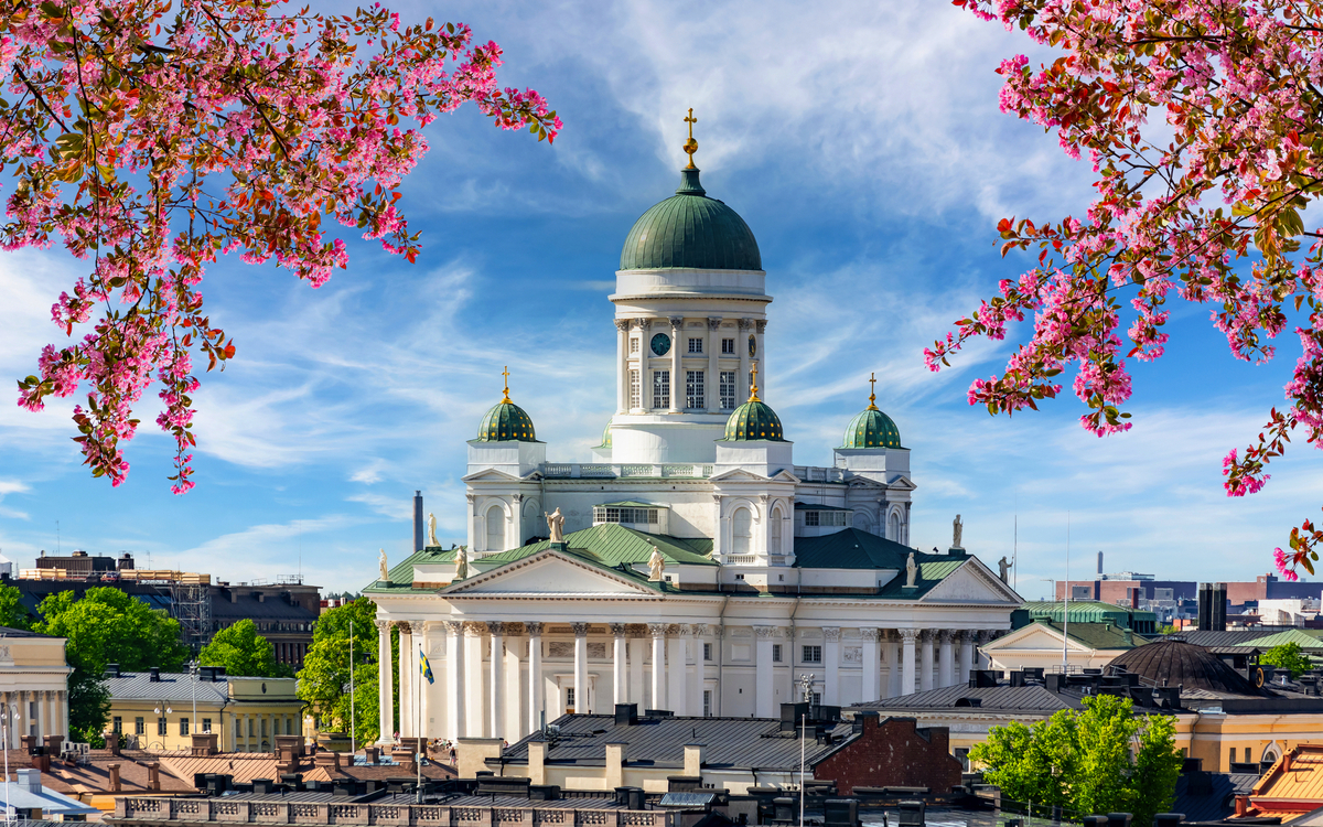 Kathedrale mit grünem Kuppeldach, umgeben von rosa Blüten und blauem Himmel.