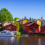 Bunte Holzhäuser am Flussufer mit Boot und blauem Himmel. Porvoo