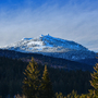 Schneebedeckter Berg mit Nadelwald im Vordergrund unter blauem Himmel Großer Arber im Bayerischen Wald