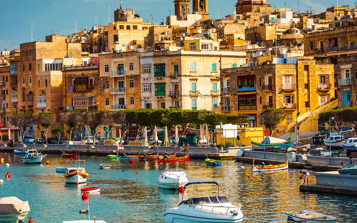 Hafen von Vittoriosa auf Malta mit Blick auf bunte Boote und historische Gebäude im Hintergrund.