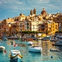 Hafen von Vittoriosa auf Malta mit Blick auf bunte Boote und historische Gebäude im Hintergrund.