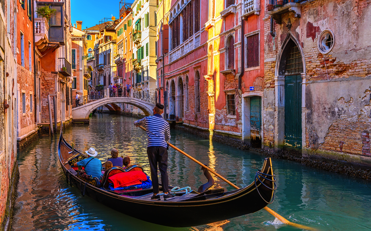 Gondel in Venedig auf einem Kanal vor bunten Häusern.