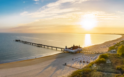 Sonnenaufgang am Ahlbecker Strand mit Blick auf die Seebrücke in Heringsdorf, Mecklenburg-Vorpommern, Deutschland.