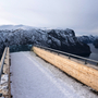 Schneegepfad mit Aussicht auf verschneite Berge und einen tiefen Fjord.