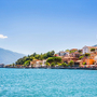 Blick auf die Stadt Limone sul Garda am Gardasee in Italien mit türkisfarbenem Wasser im Vordergrund und historischen Gebäuden im Hintergrund.