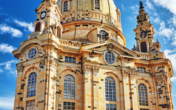 Eine barocke Kirche mit großer Kuppel und reich verzierten Fassaden unter einem blauen Himmel.