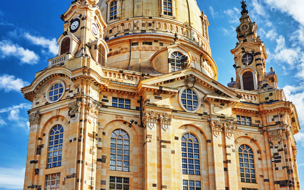 Eine barocke Kirche mit großer Kuppel und reich verzierten Fassaden unter einem blauen Himmel.
