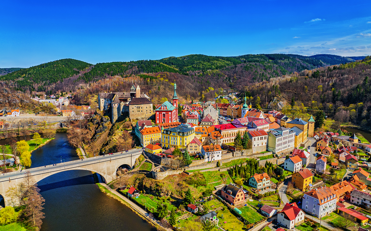 Loket Luftaufnahme einer bunten Kleinstadt mit Brücke und Fluss in einer hügeligen Landschaft.