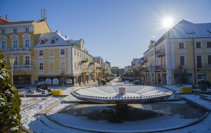 Franzensbad Winterliche Stadtstraße mit Brunnen und Sonne am klaren Himmel.