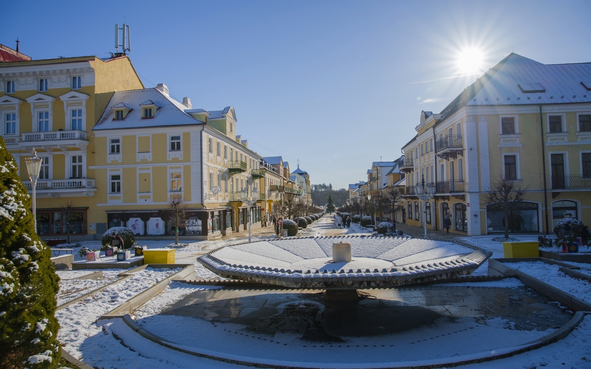 Franzensbad Winterliche Stadtstraße mit Brunnen und Sonne am klaren Himmel.