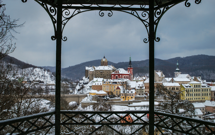 Loket Winterliche Stadtansicht mit Burg und Kirche, umrahmt von einem Pavillon.