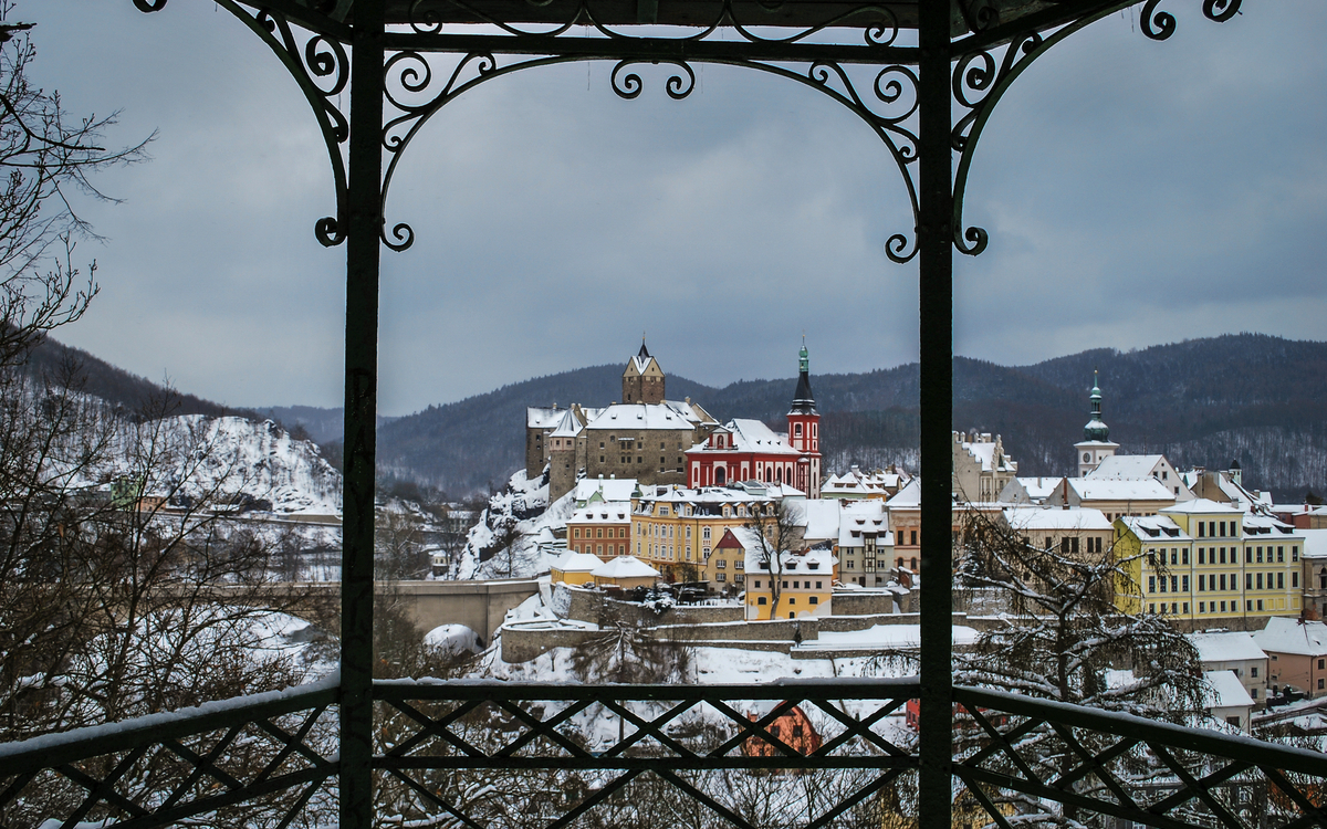 Loket Winterliche Stadtansicht mit Burg und Kirche, umrahmt von einem Pavillon.