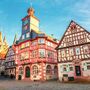 Historische Fachwerkhäuser mit Turm und Uhr in einer Altstadt.