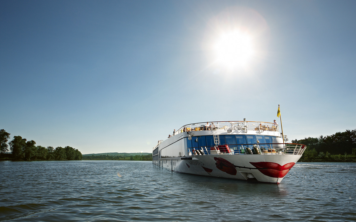 Ein Flussschiff der A-ROSA Flotte fährt bei Sonnenschein über die Rhone.