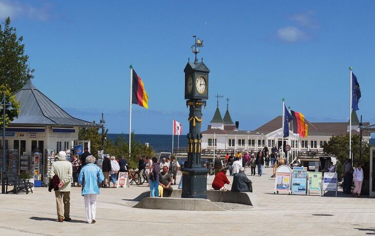 Menschen flanieren auf der Seebrücke in Ahlbeck, Deutschland, bei sonnigem Wetter.